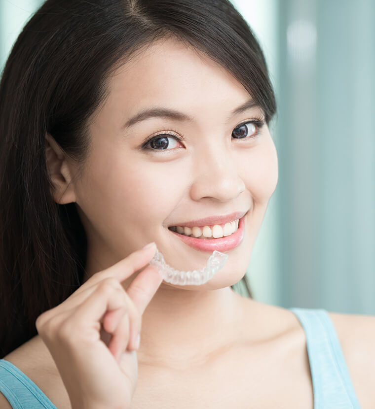 woman holding up a clear aligner