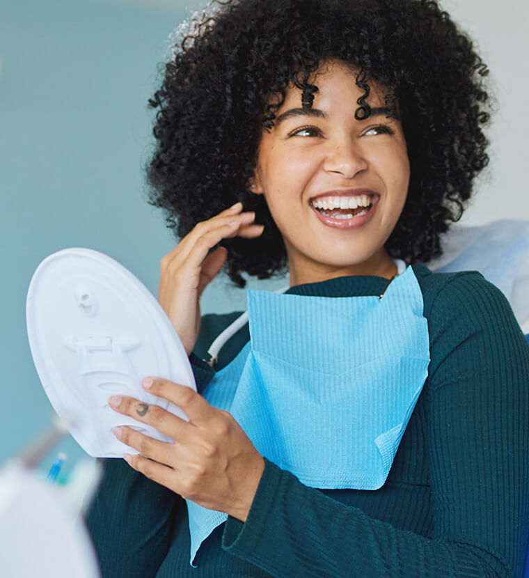 woman examining her smile in a mirror