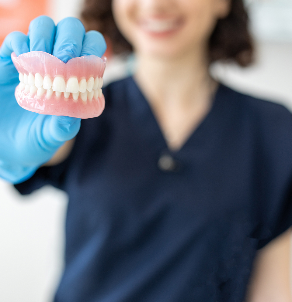 dentist holding dentures toward the camera